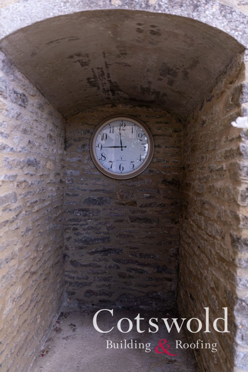 Cotswold stone arch featuring old clock by Cotswold Building and Roofing Ltd