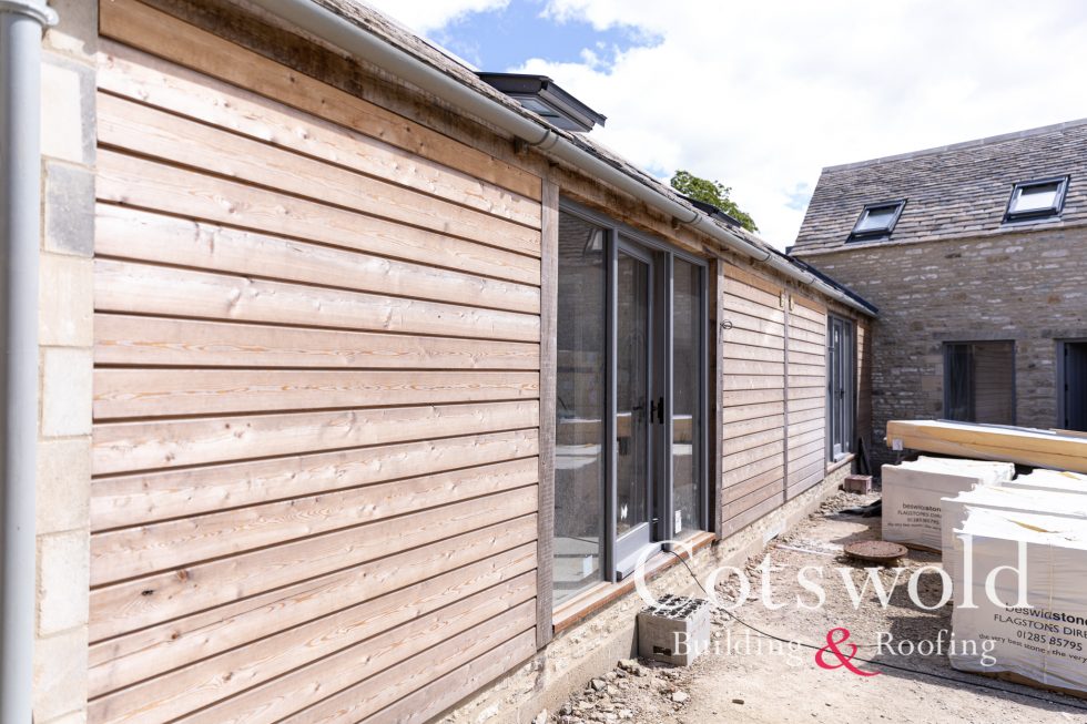 Barn conversion with wood clad outside by Cotswold Building and Roofing Ltd